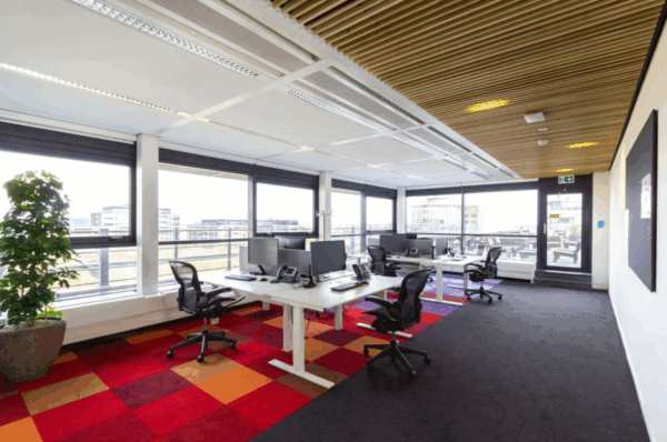 Modern kantoor op Boeing Avenue met grote ramen, bureau-opstellingen en kleurrijke vloerbedekking.