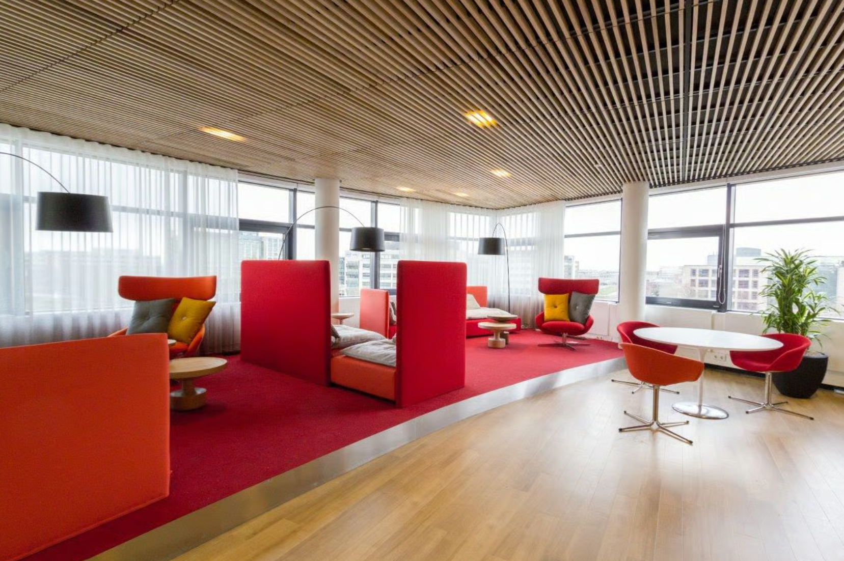 Moderne, kleurrijke lounge- en werkruimte met rood tapijt, designstoelen en grote ramen in een kantoor aan de Boeing Avenue.