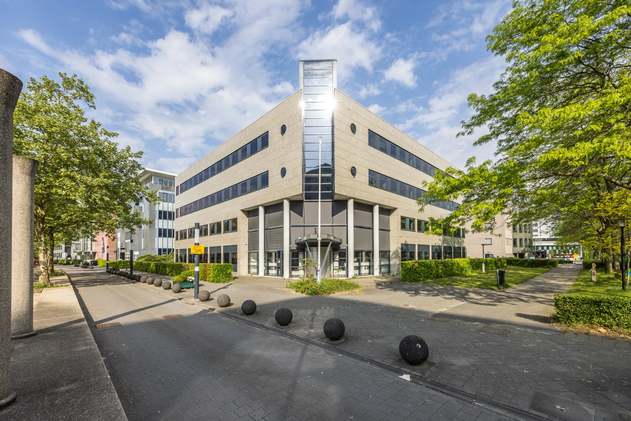 Modern kantoorgebouw aan de Varrolaan met glazen entree en omliggend groen.