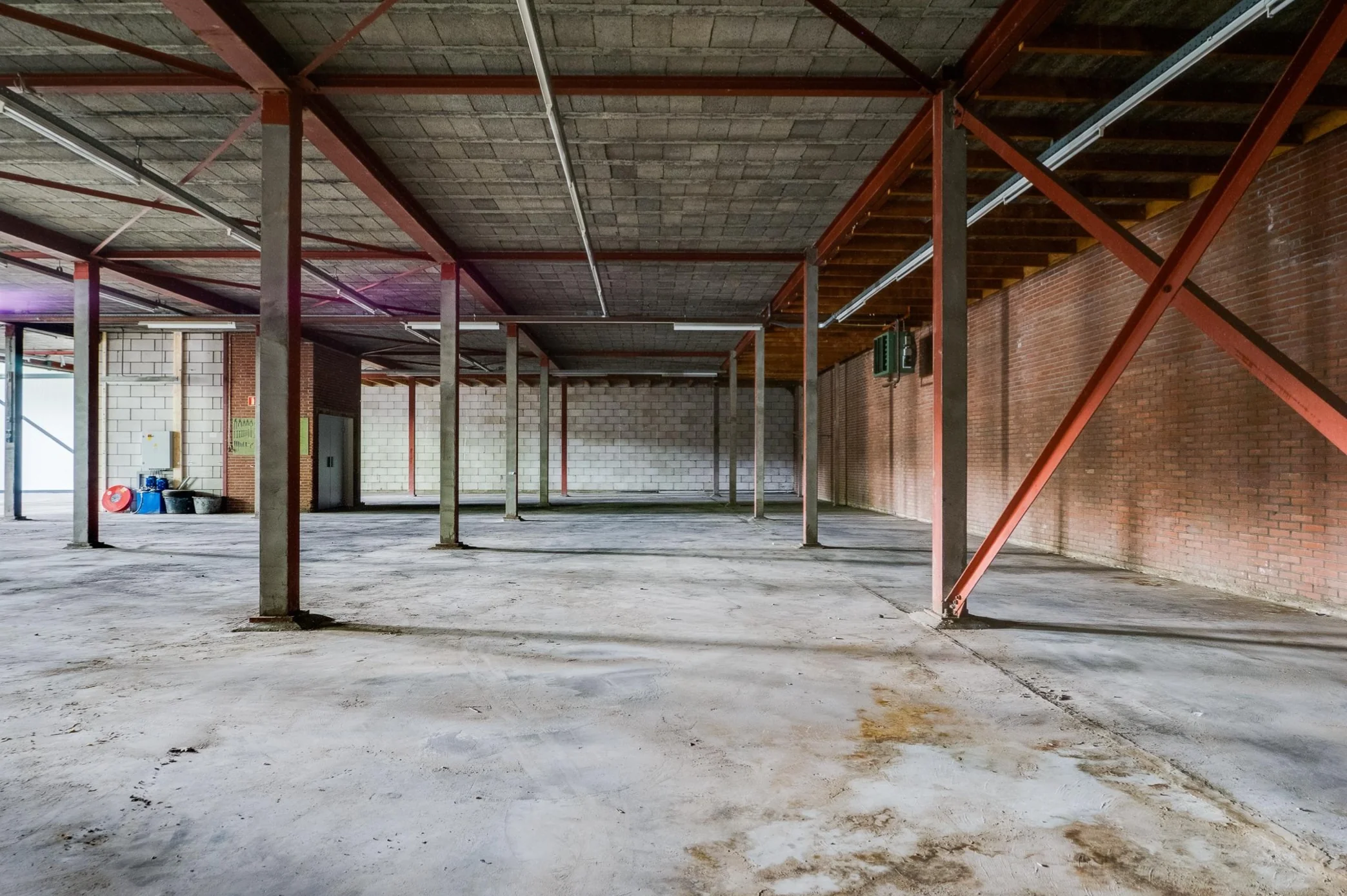 Lege industriële loods aan de Australiëlaan met betonnen vloer, metalen steunpilaren en bakstenen muren.