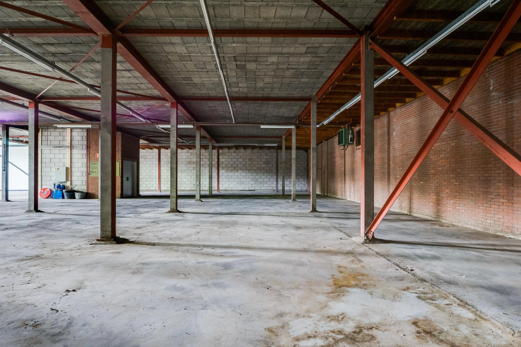 Leegstaand industrieel magazijn met betonnen vloer, stalen draagconstructie en bakstenen muren aan de Australielaan.