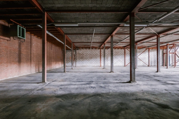 Lege bedrijfsruimte met betonnen vloer, bakstenen muur en stalen draagconstructie aan de Australielaan.