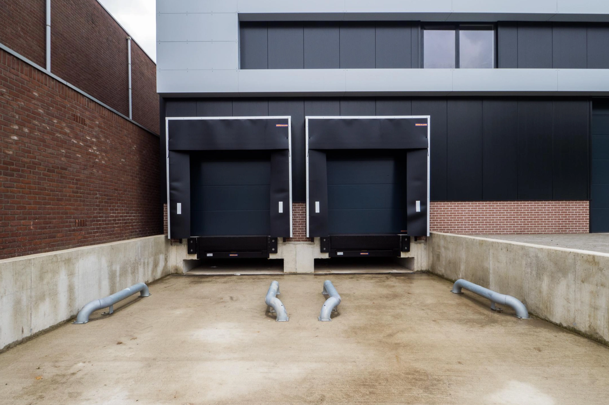 Twee laadperrons met gesloten dockdeuren aan de achterzijde van een industrieel gebouw aan de Australielaan.