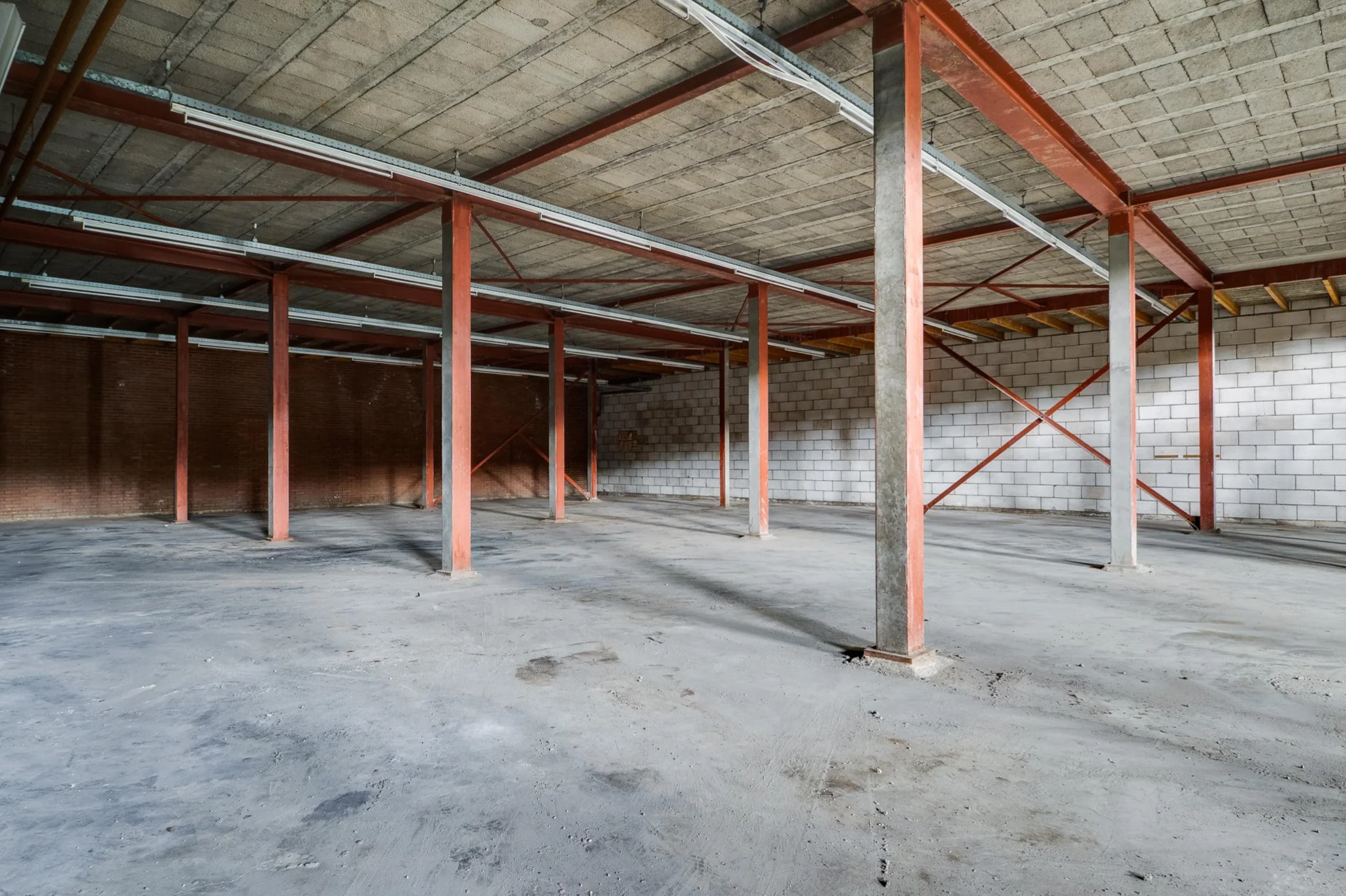 Lege industrieel ogende bedrijfsruimte aan de Australiëlaan met betonnen vloer, stalen balken en bakstenen muren.