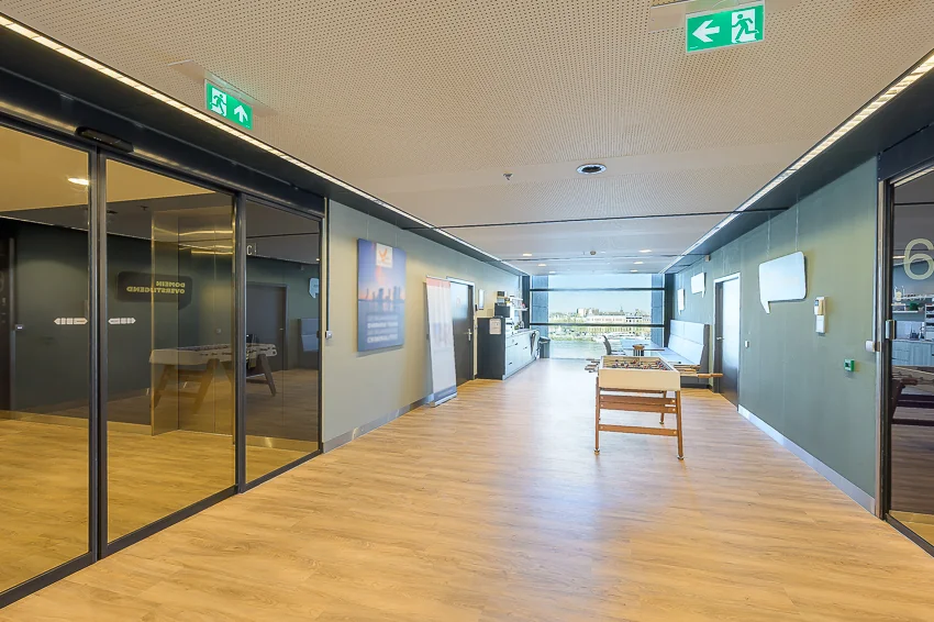 Modern ingerichte kantoorruimte aan de Wilhelminakade met zithoek, tafelvoetbaltafel en uitzicht op de stad.