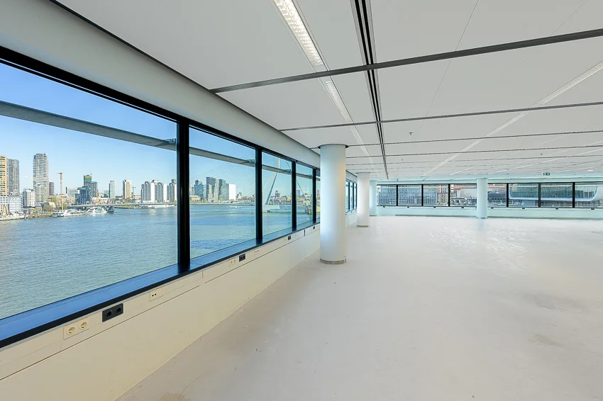Licht en open kantoorruimte aan de Wilhelminakade met panoramisch uitzicht op de skyline van Rotterdam en de Maas.