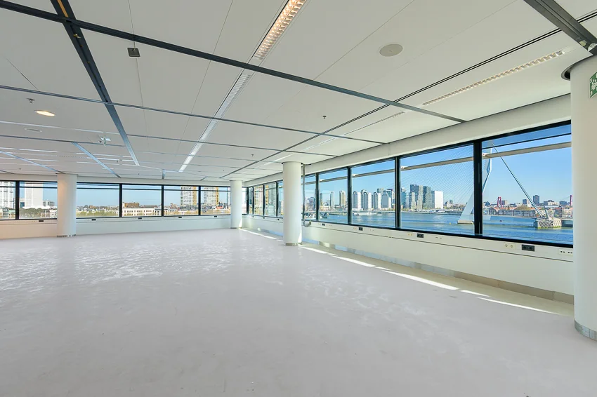 Lichte, lege kantoorruimte aan de Wilhelminakade met panoramisch uitzicht op de skyline van Rotterdam en de Erasmusbrug.
