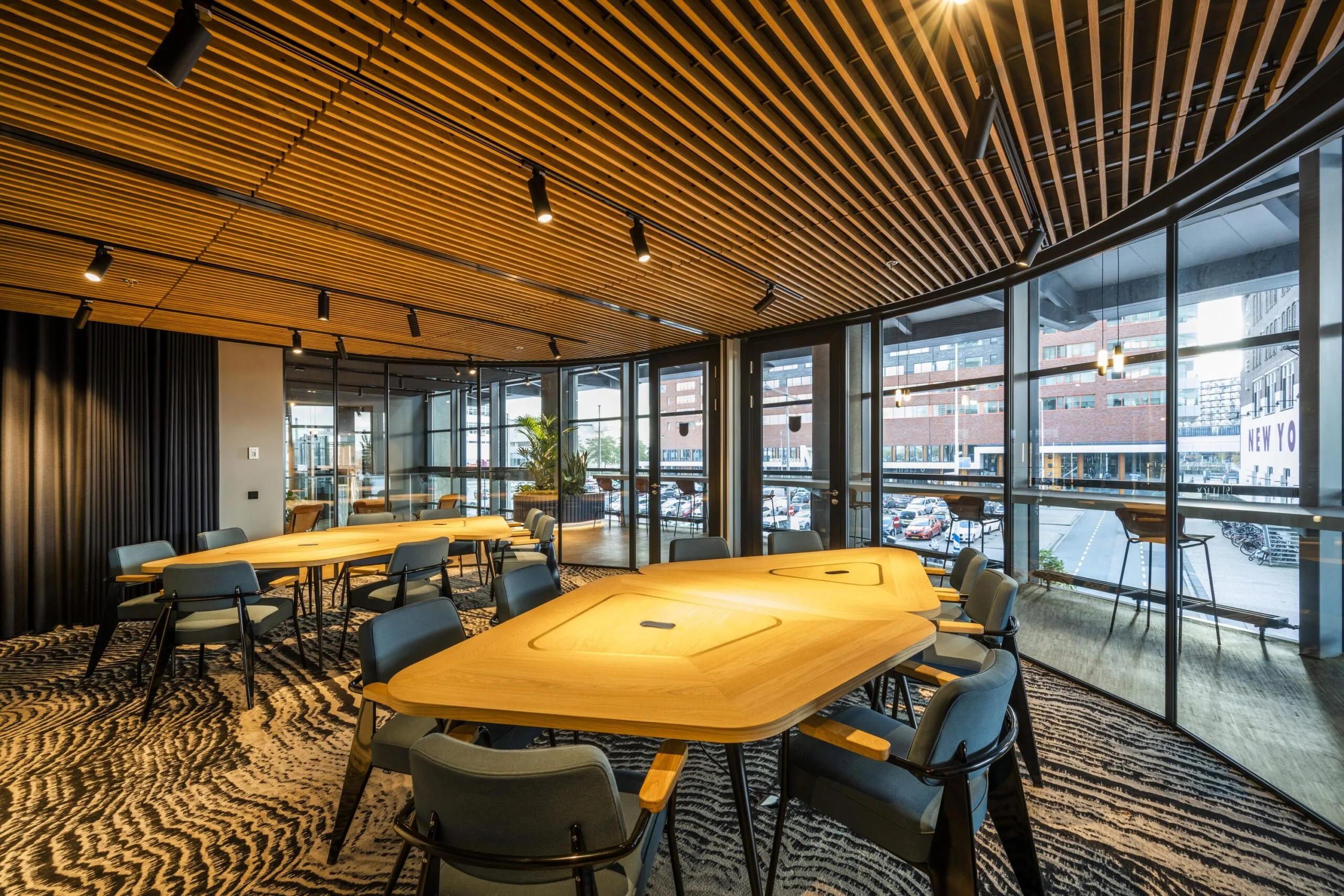 Moderne vergaderruimte aan de Wilhelminakade met houten plafond, designmeubilair en uitzicht op de stad.