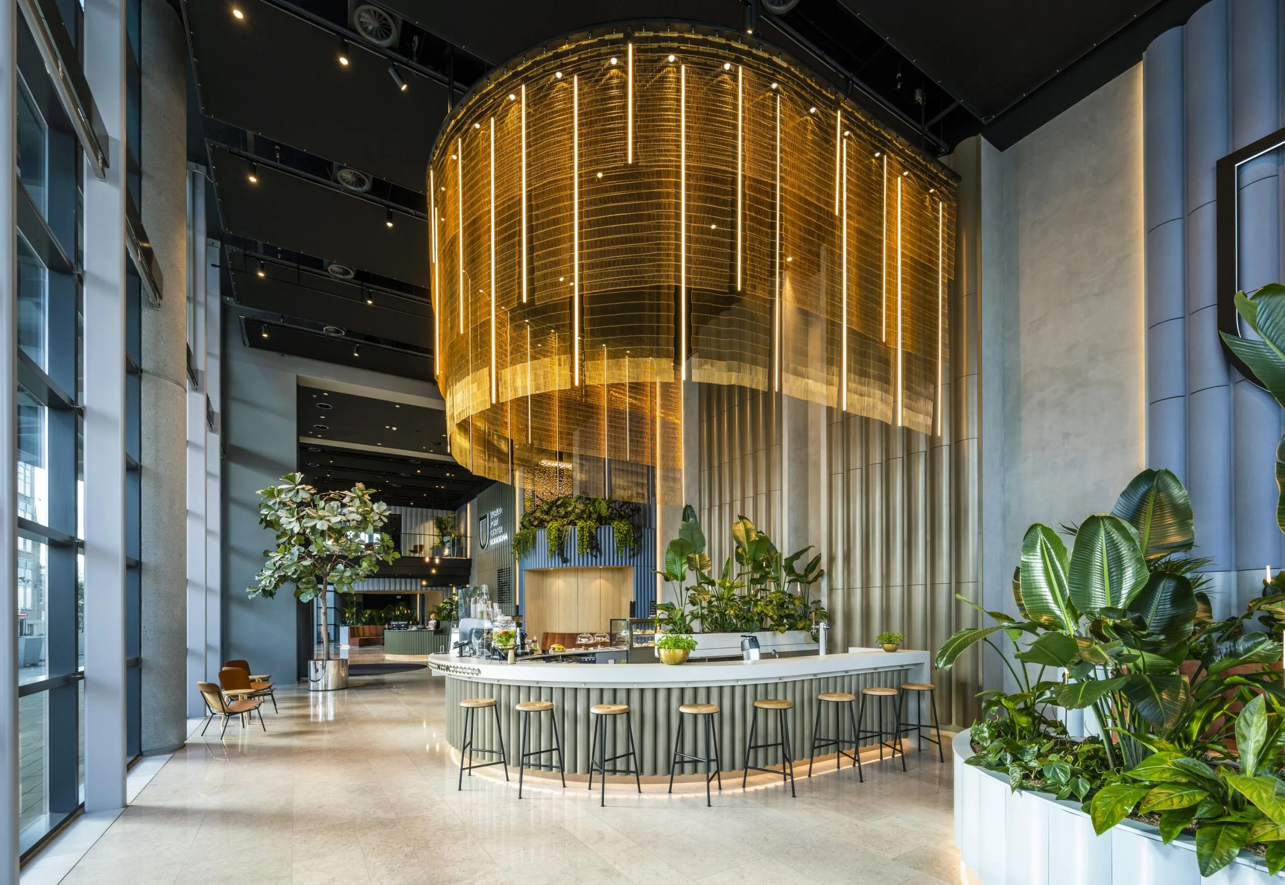 Moderne en sfeervol verlichte lobby aan de Wilhelminakade met een ronde bar, hoge plafonds en veel groen.
