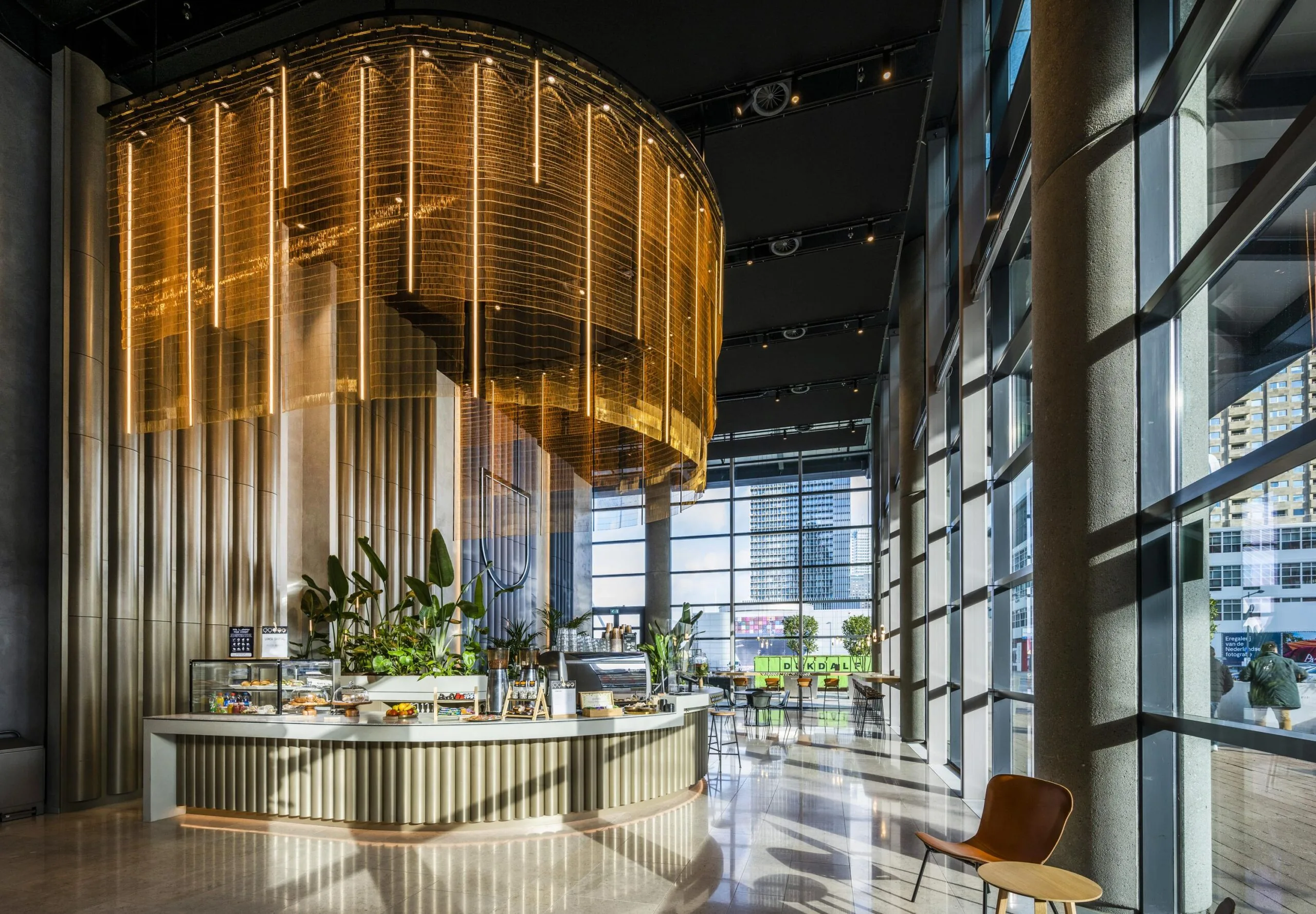 Modern ingericht café met goudkleurige accenten in een lichte ruimte aan de Wilhelminakade in Rotterdam.