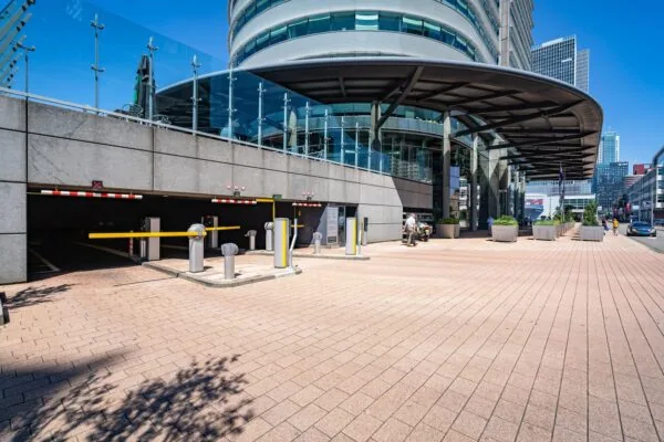 Ingang van een ondergrondse parkeergarage aan de Wilhelminakade in Rotterdam met moderne bebouwing op de achtergrond.