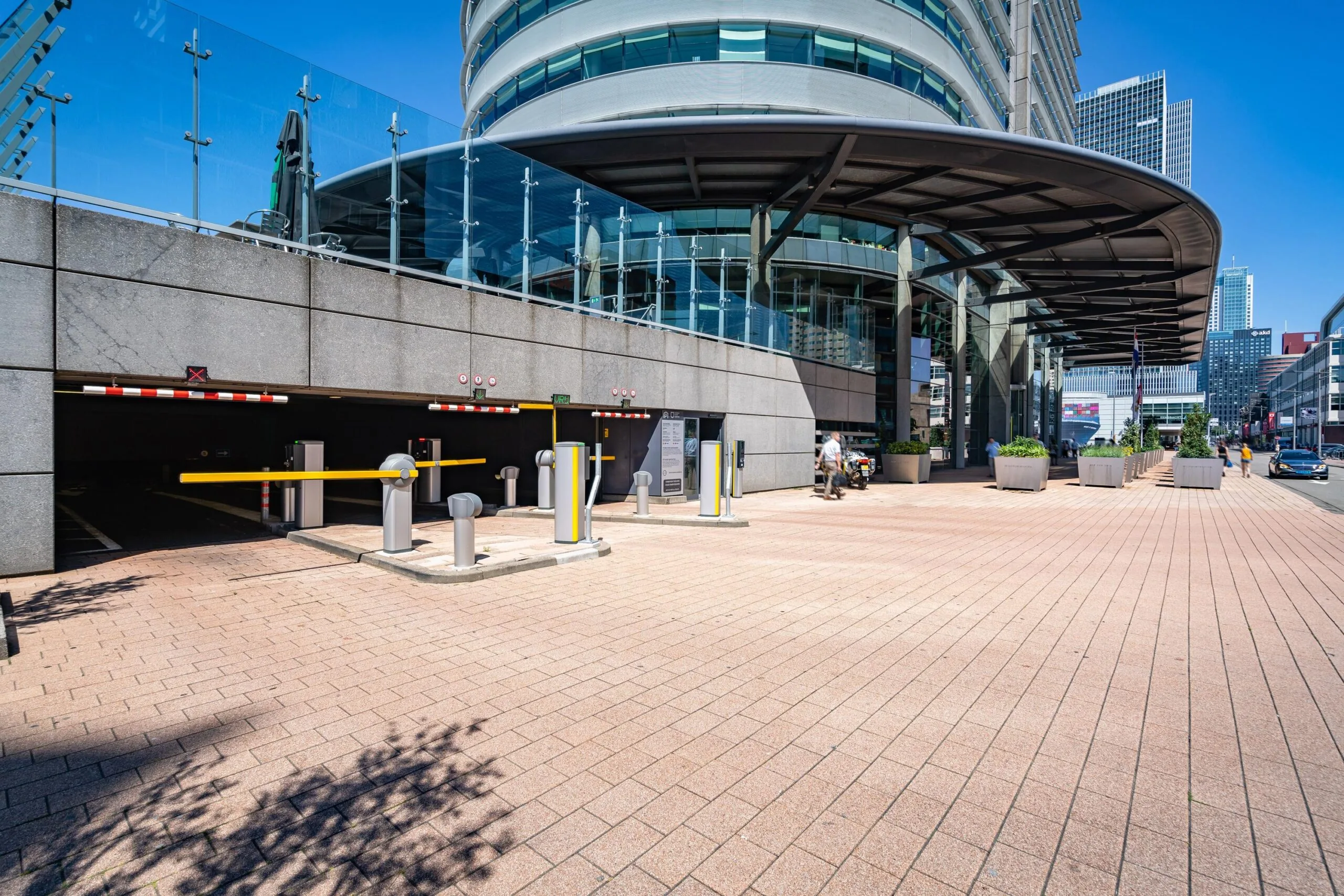 Ingang van een ondergrondse parkeergarage aan de Wilhelminakade in Rotterdam met moderne bebouwing op de achtergrond.