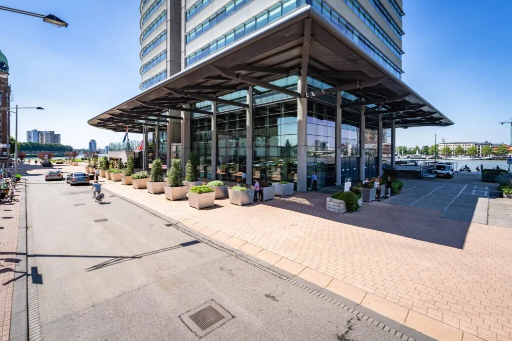 Ingang van een modern kantoorgebouw aan de Wilhelminakade in Rotterdam op een zonnige dag.