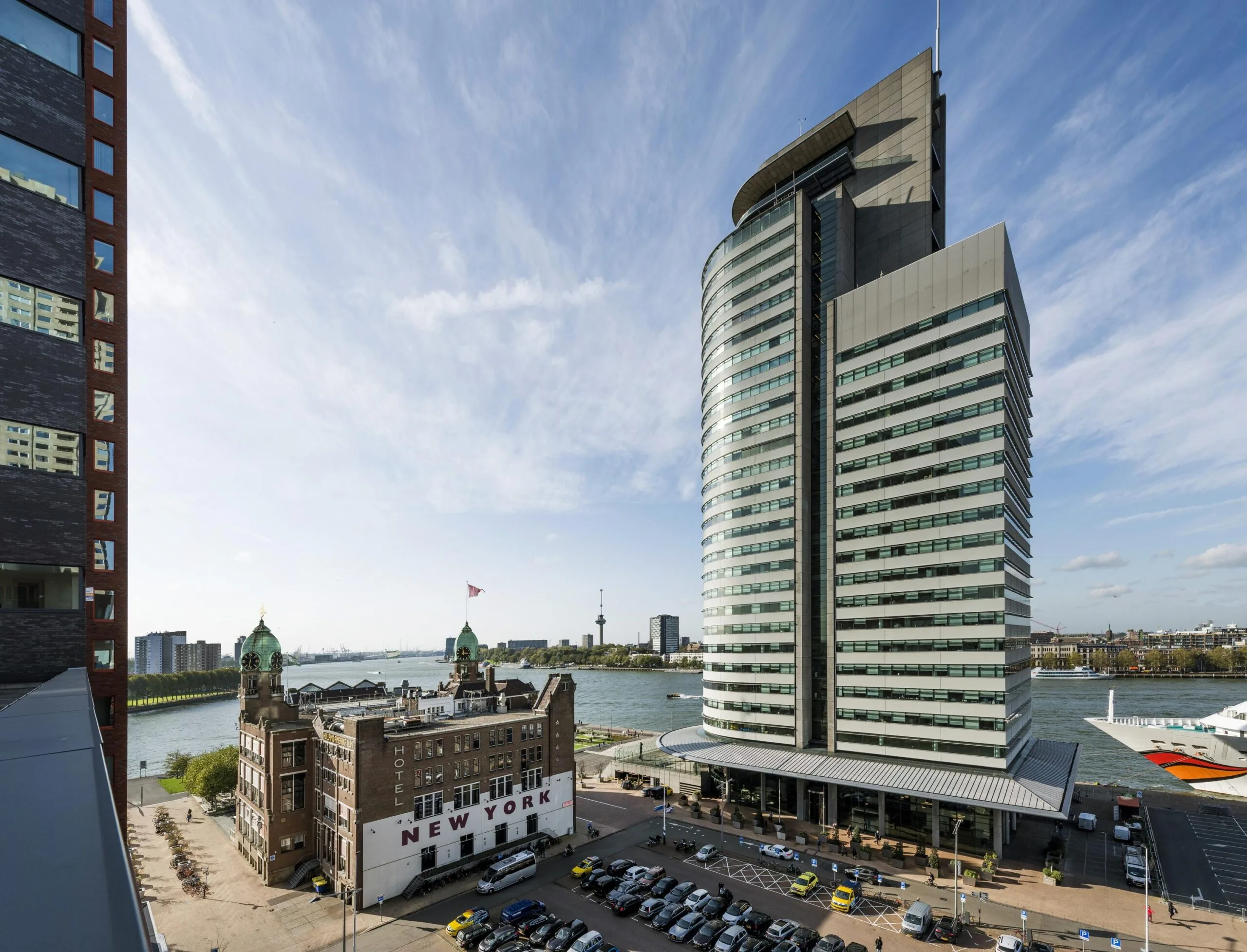 Uitzicht op de Wilhelminakade in Rotterdam met Hotel New York en het moderne kantoorgebouw De Rotterdam aan de rivier.