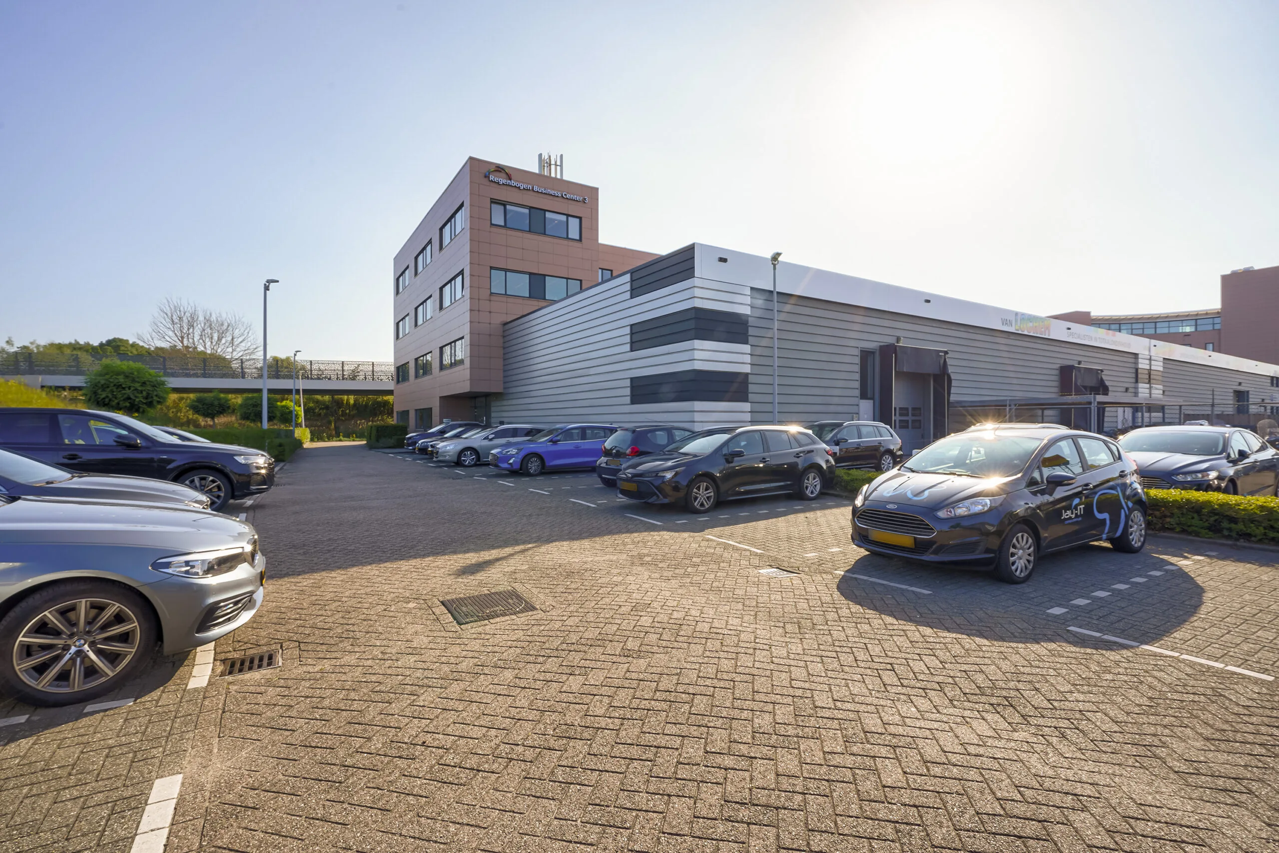 Parkeerterrein met geparkeerde auto's voor het Regenboog Business Center aan de Laan van 's-Gravenmade.