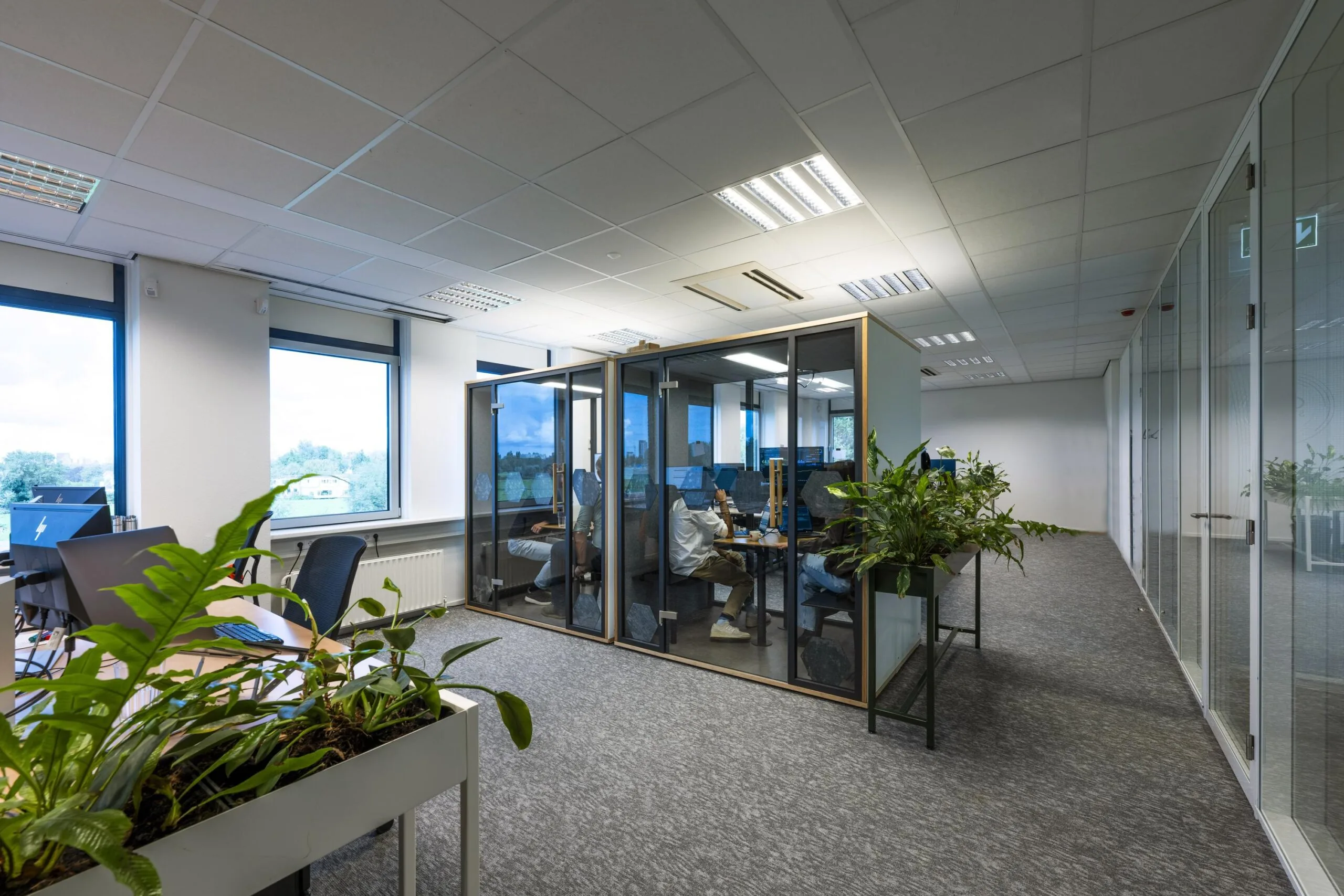 Moderne kantoorruimte met bureaus, vergaderpods en veel groenvoorziening bij Oranjebaan.