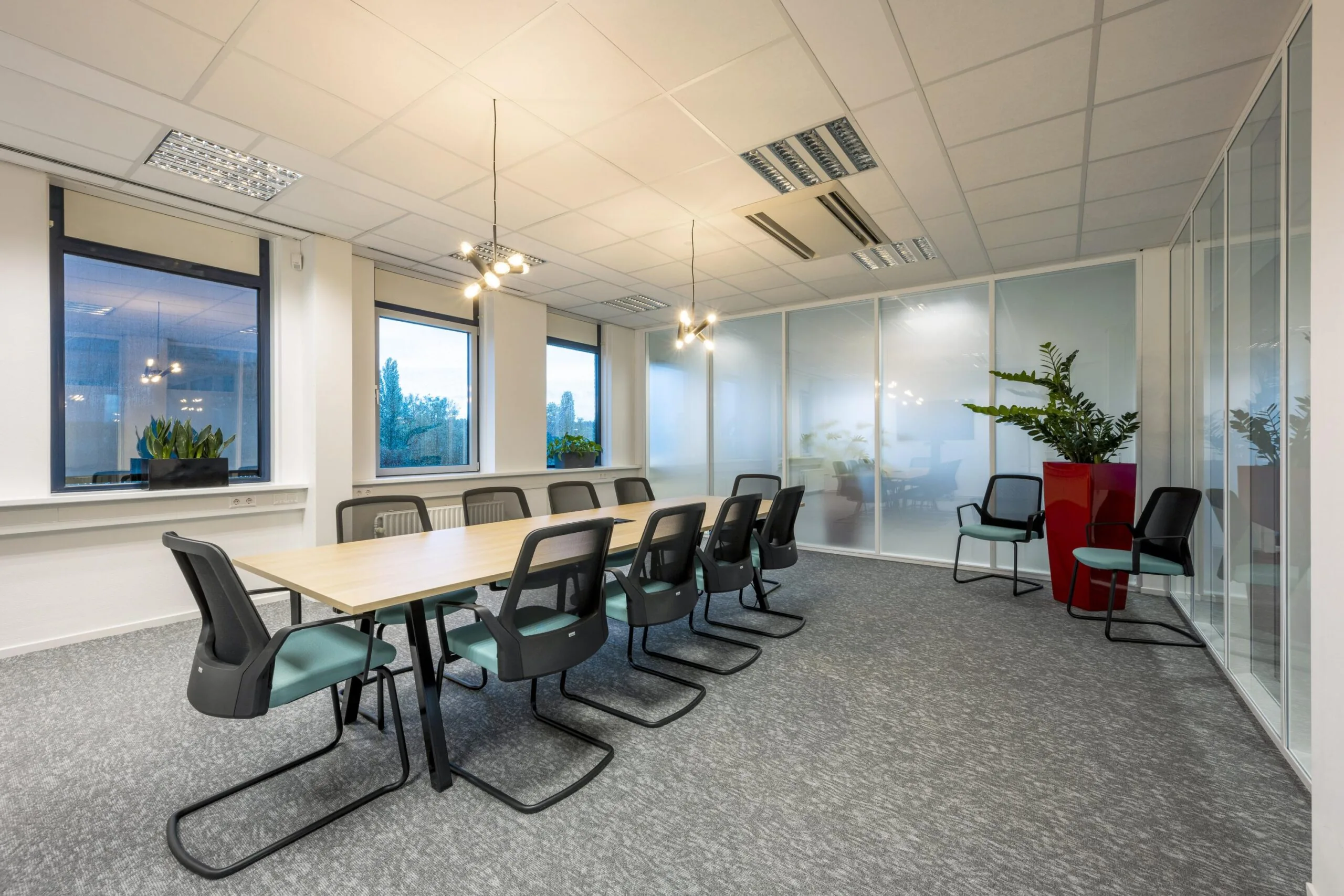Moderne vergaderruimte op Oranjebaan met lange tafel, ergonomische stoelen, grote ramen en glazen wanden.