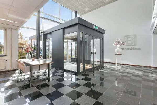 Moderne, lichte entreehal van een kantoorpand aan de Hoefsmidstraat met glazen entree, zwart-wit geblokte vloer en stijlvolle bloemen decoratie.