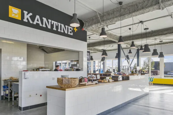 Moderne, lichte bedrijfskantine aan de Hoefsmidstraat met een open keuken en een toonbank vol etenswaren.