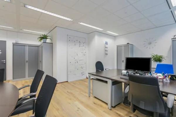 Modern kantoor met bureaus, kasten, en wand met technische tekeningen aan de Hoefsmidstraat.