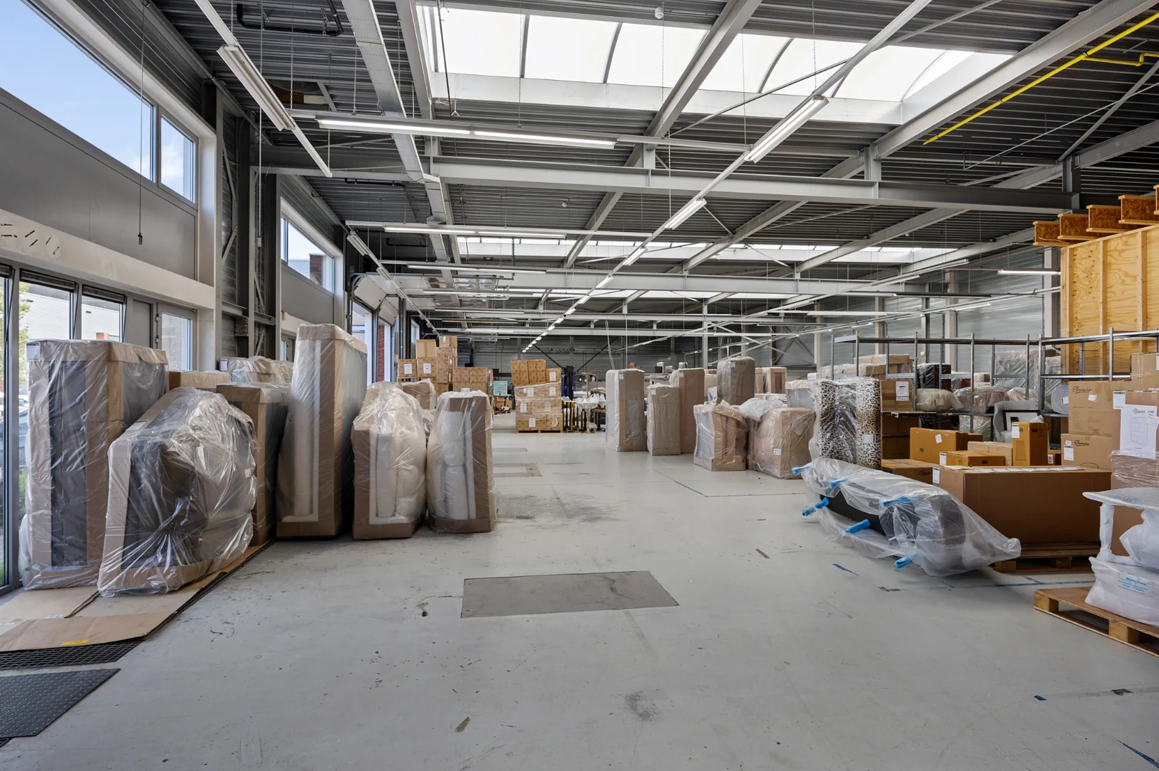 Ruim en licht industrieel magazijn aan de Schaafstraat met ingepakte meubels en dozen op pallets.