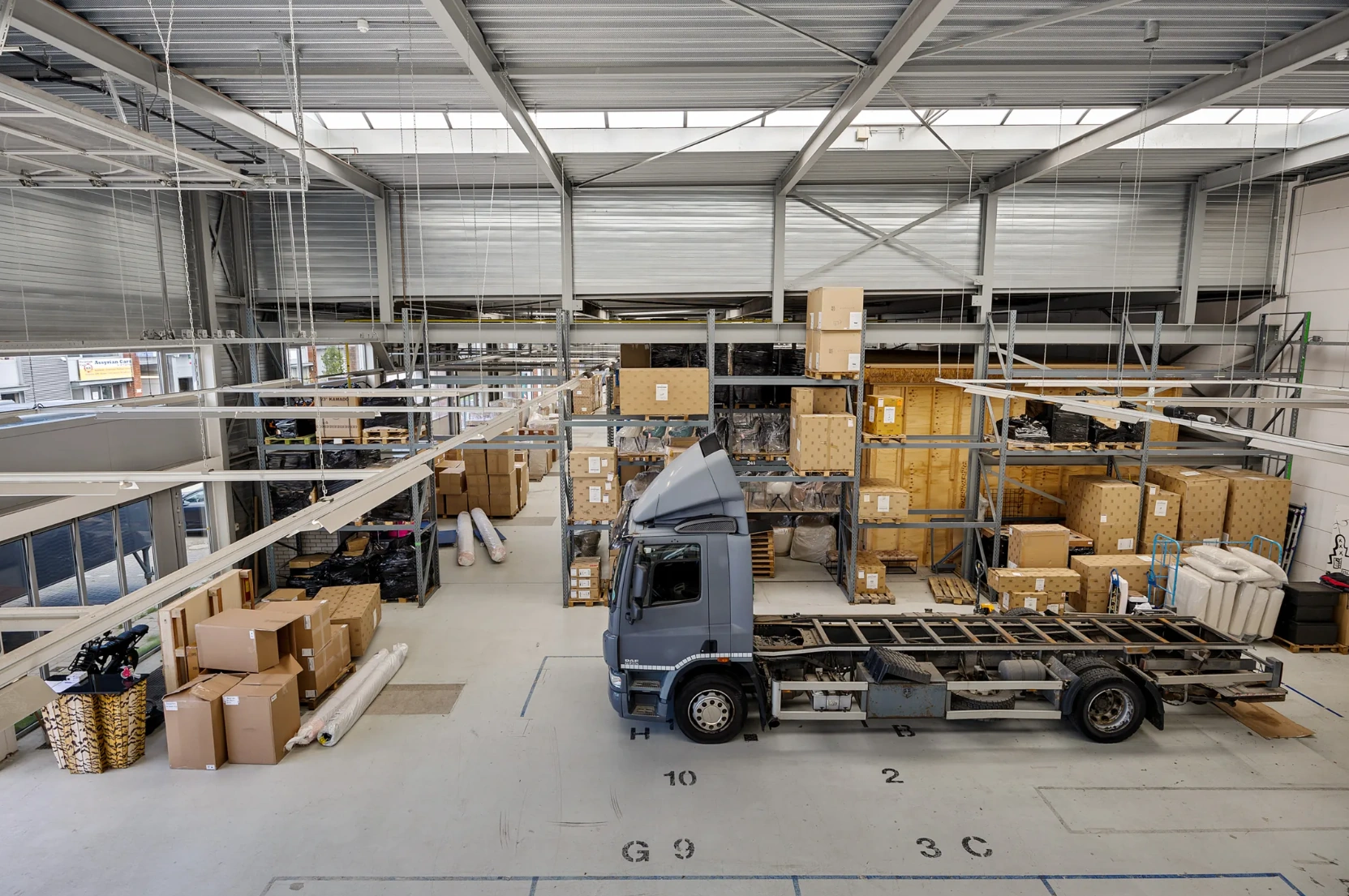 Magazijn aan de Schaafstraat met stellingen vol dozen en een vrachtwagen zonder oplegger in het midden van de ruimte.
