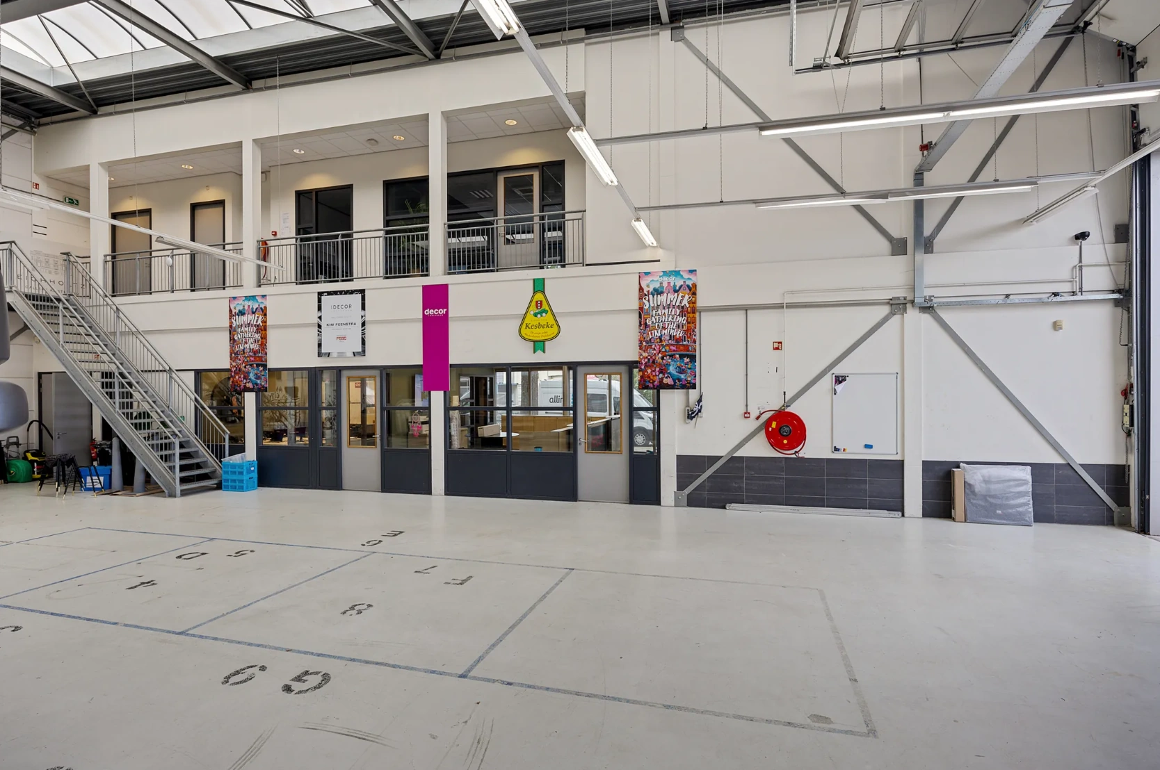 Ruime, industriële binnenruimte aan de Schaafstraat met kantoorunits op de eerste verdieping en decoratieve posters aan de muur.