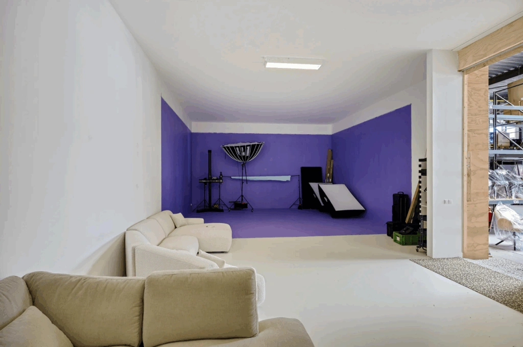 Fotostudio aan de Schaafstraat met paarse achtergrond, studioverlichting en een zithoek met beige banken.