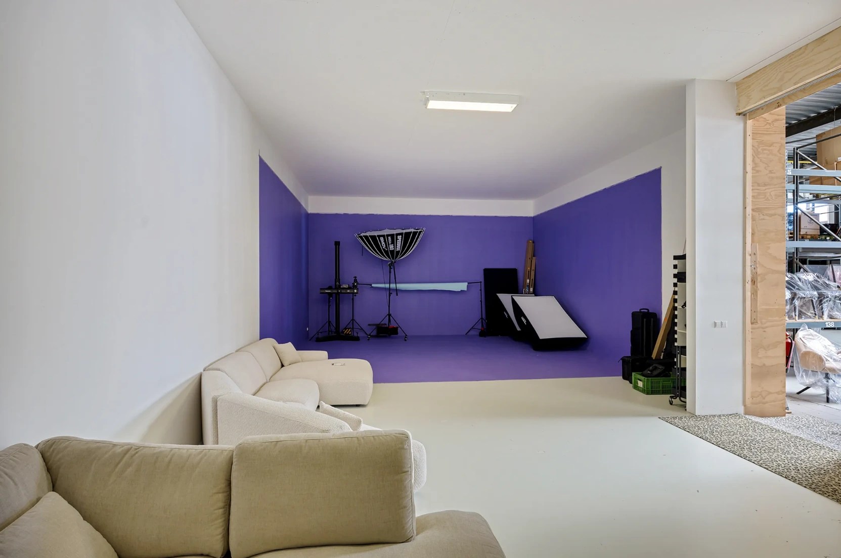 Fotostudio aan de Schaafstraat met paarse achtergrond, studioverlichting en een zithoek met beige banken.