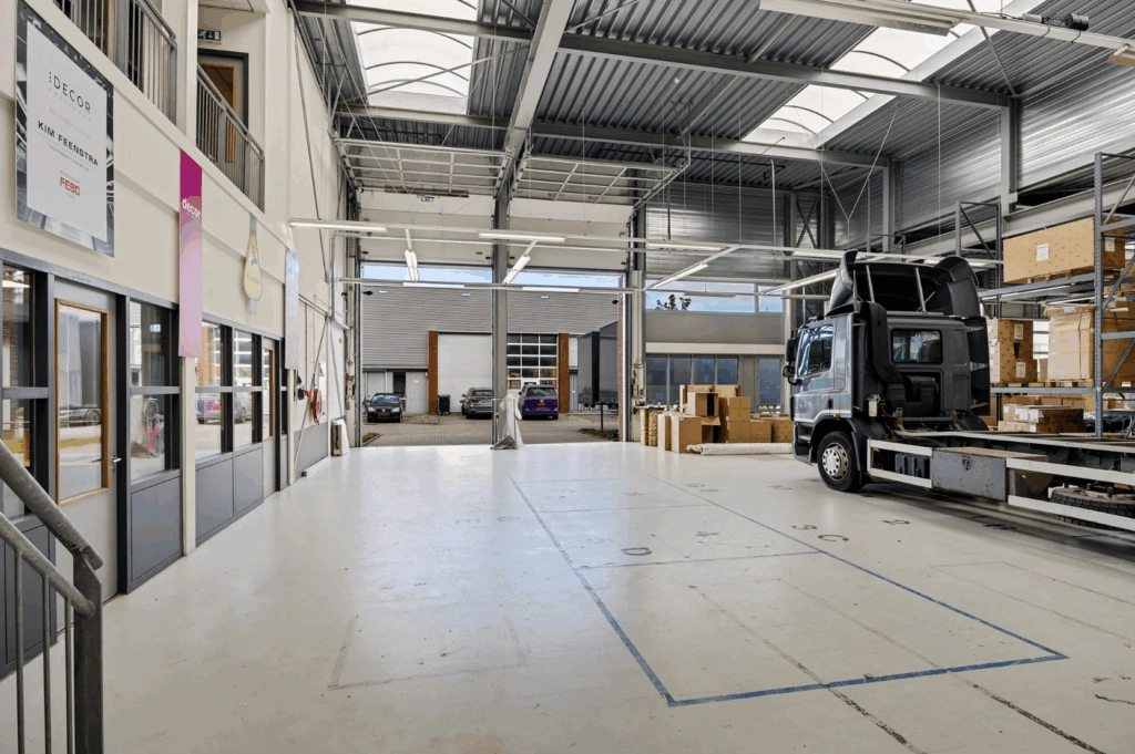 Interieur van een moderne bedrijfsloods aan de Schaafstraat met een vrachtwagen, rekken met dozen en kantoorruimtes.