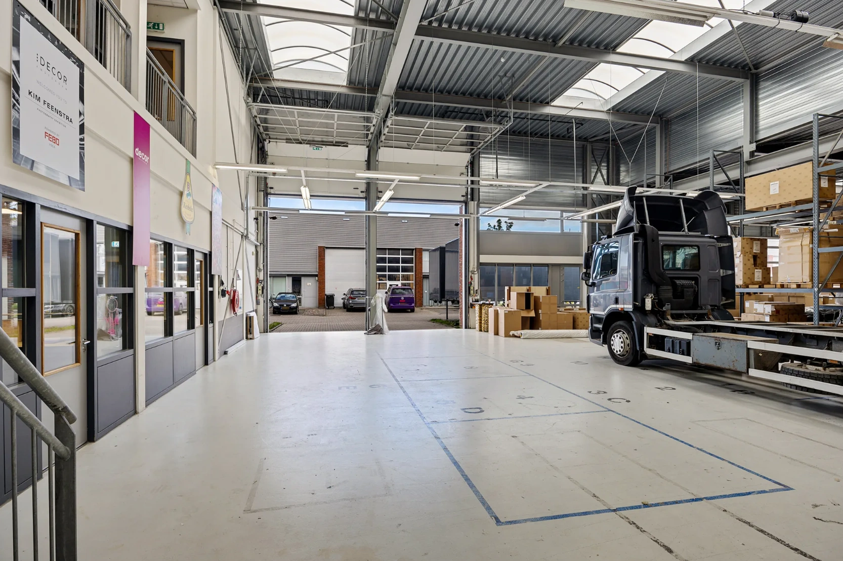 Interieur van een moderne bedrijfsloods aan de Schaafstraat met een vrachtwagen, rekken met dozen en kantoorruimtes.