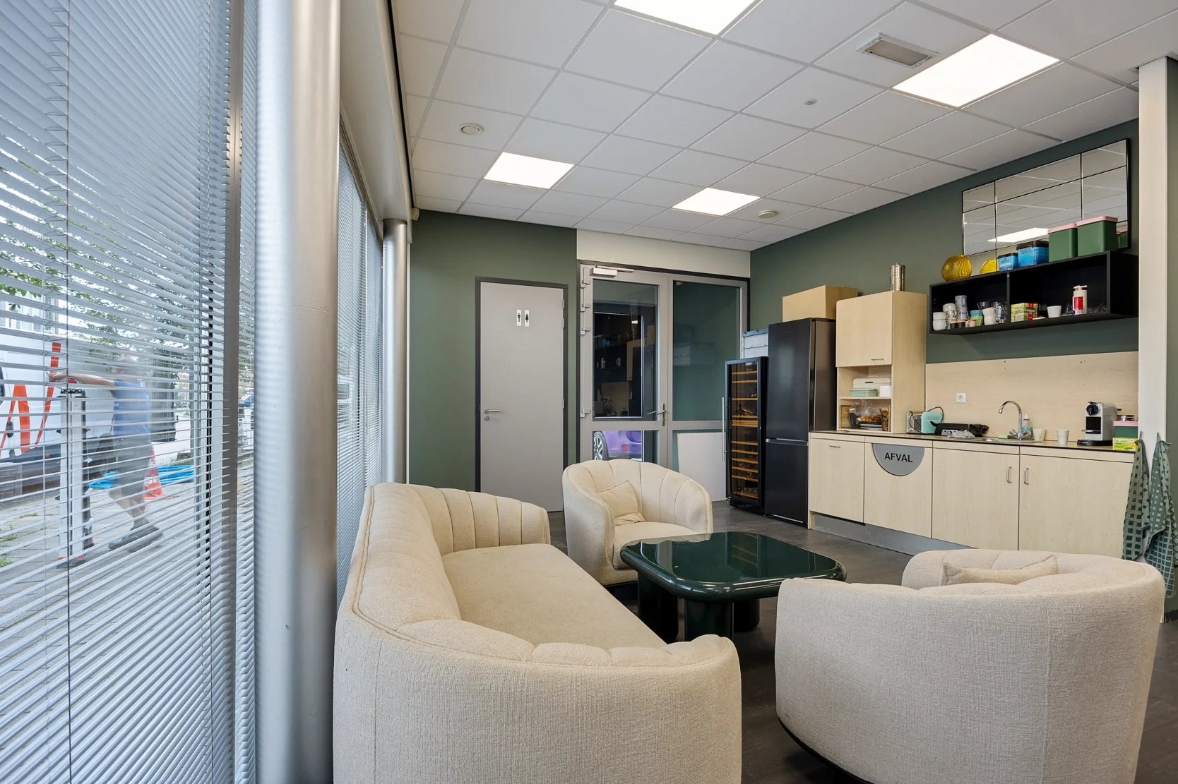 Modern ingerichte kantineruimte aan de Schaafstraat met zithoek, kitchenette en grote raampartijen met jaloezieën.