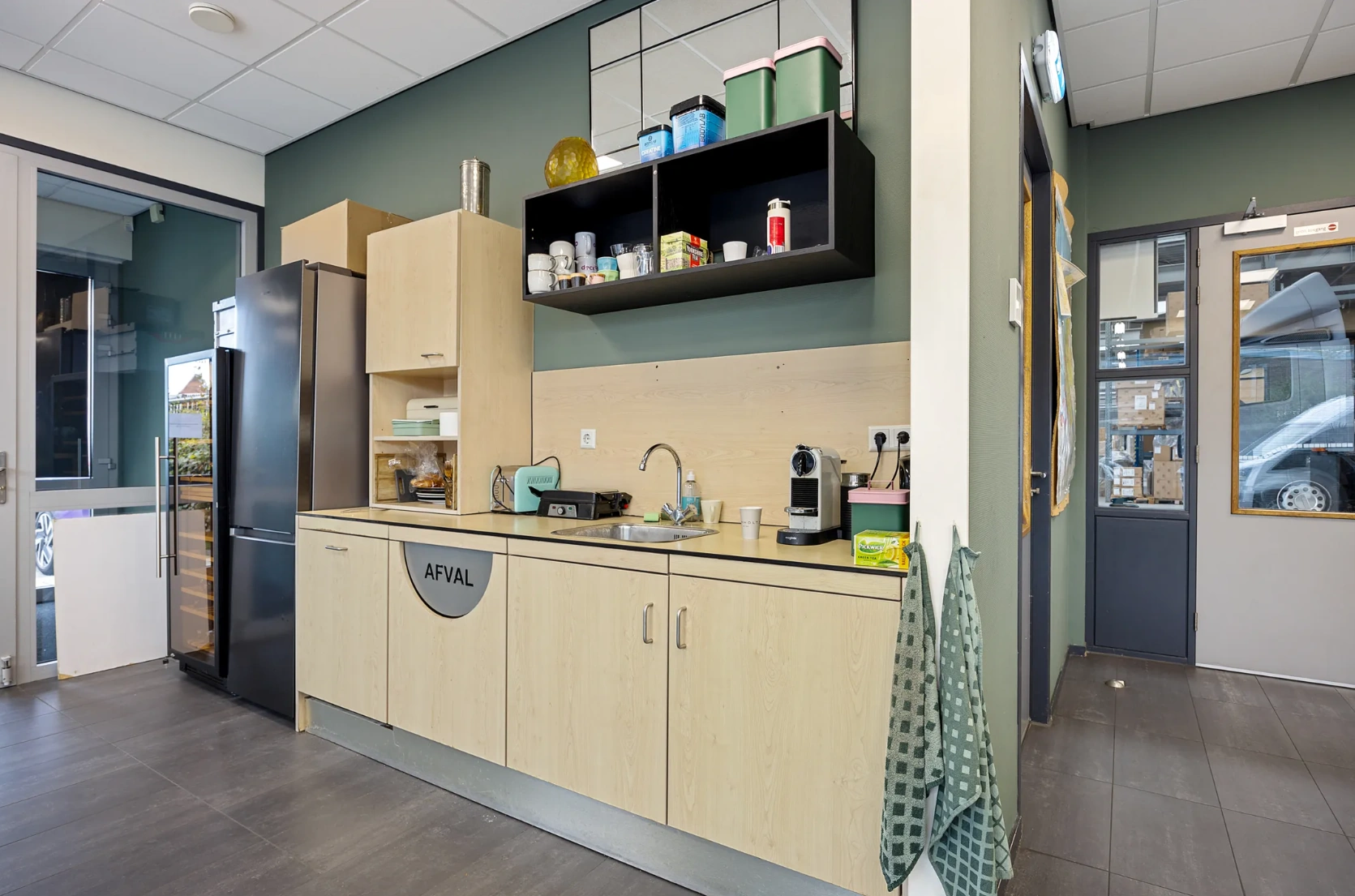 Moderne bedrijfskeuken met koelkast, koffiezetapparaat, gootsteen en opbergruimte aan de Schaafstraat.
