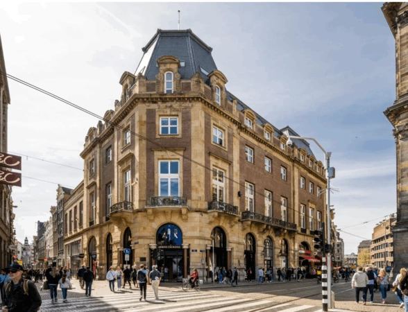 Straatbeeld van de Paleisstraat in Amsterdam met het monumentale hoekpand waarin Armani Exchange is gevestigd.