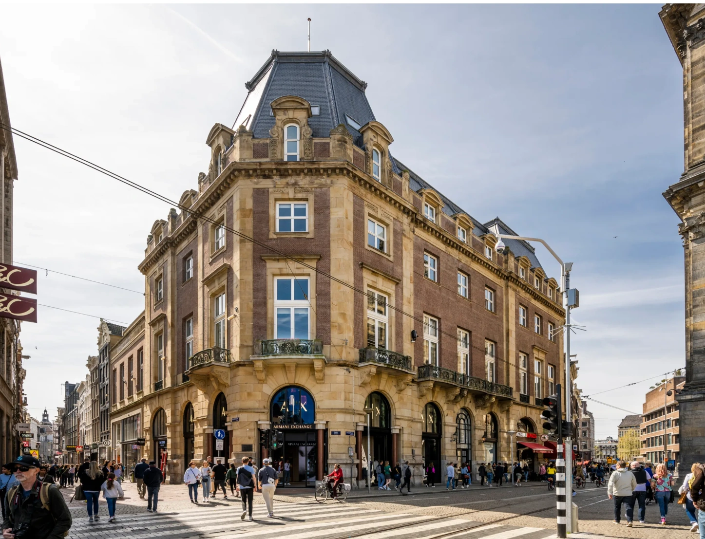 Straatbeeld van de Paleisstraat in Amsterdam met het monumentale hoekpand waarin Armani Exchange is gevestigd.