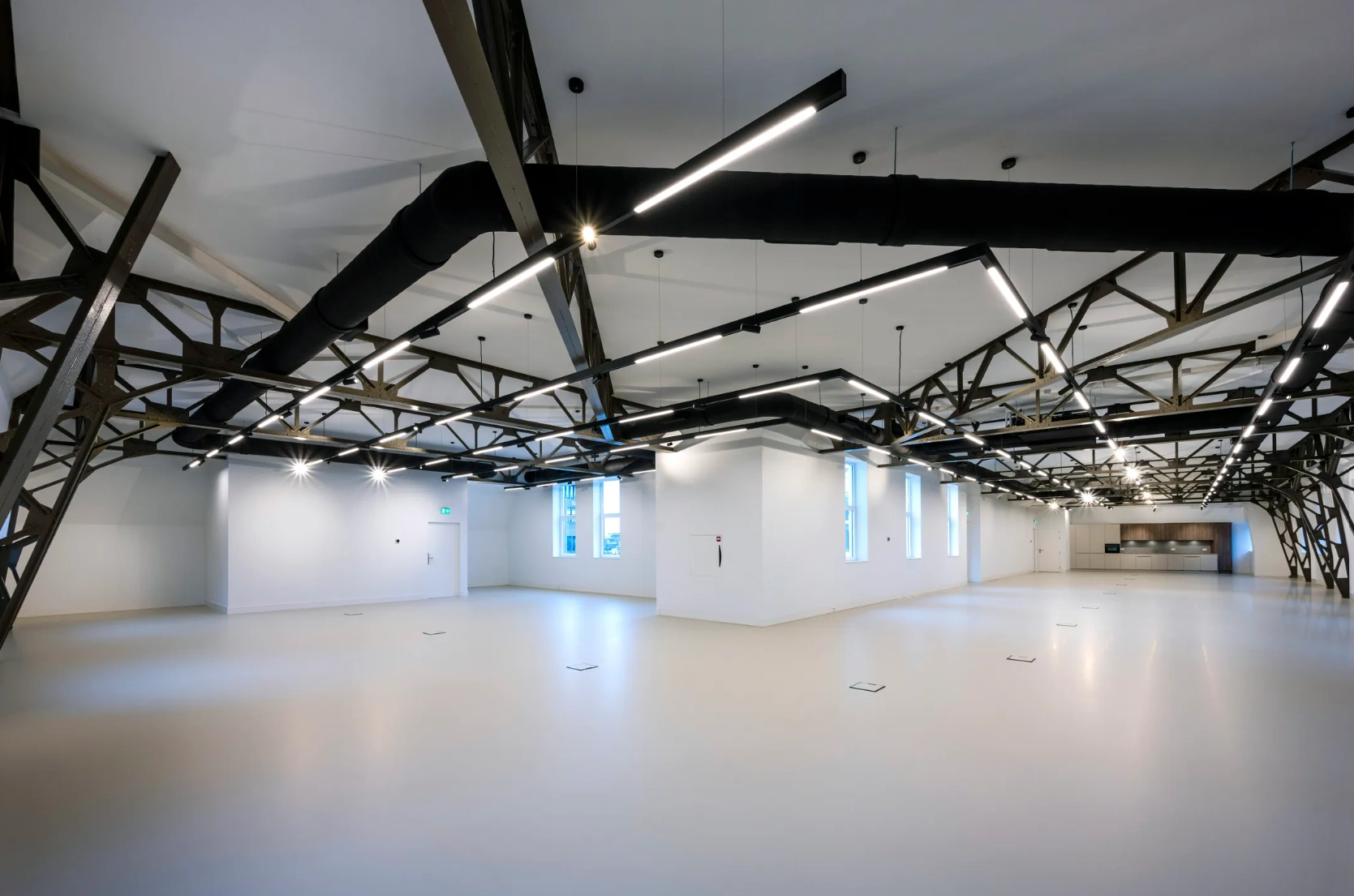 Moderne, ruime binnenruimte in Paleisstraat met industriële plafondelementen en strakke verlichting.