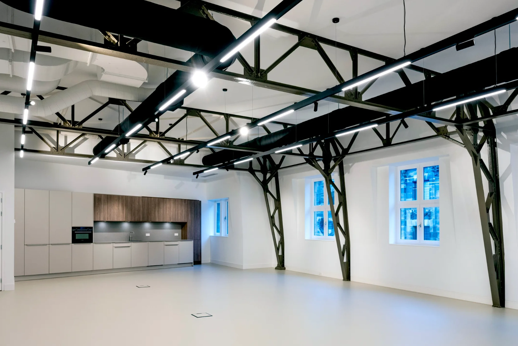 Moderne, industriële kantoorruimte aan de Paleisstraat met open plafondconstructie, strakke verlichting en ingebouwde keuken.