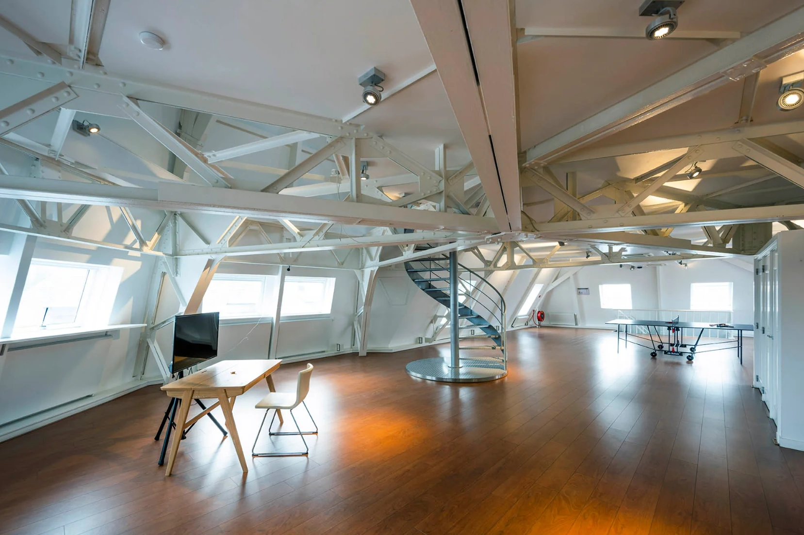 Moderne kantoorruimte aan de Paleisstraat met zichtbare dakconstructie, houten vloer, wenteltrap en pingpongtafel.