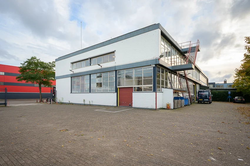 Wit industriepand aan de Linschotenstraat met grote ramen en een externe trap aan de zijkant.