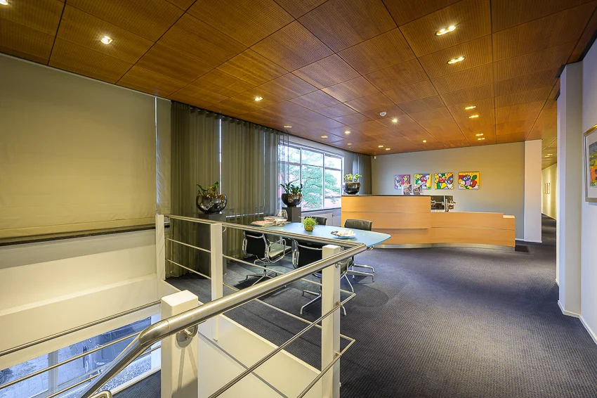 Modern ingerichte kantoorruimte aan de Linschotenstraat met receptiebalie, vergadertafel en kleurrijke kunst aan de muur.
