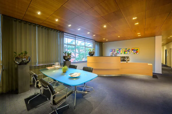 Moderne kantoorruimte aan de Linschotenstraat met een ontvangstbalie, vergadertafel en kleurrijke kunst aan de muur.
