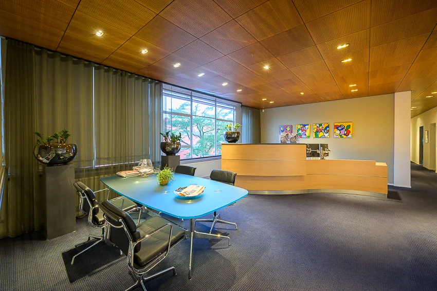 Moderne kantoorruimte aan de Linschotenstraat met een ontvangstbalie, vergadertafel en kleurrijke kunst aan de muur.