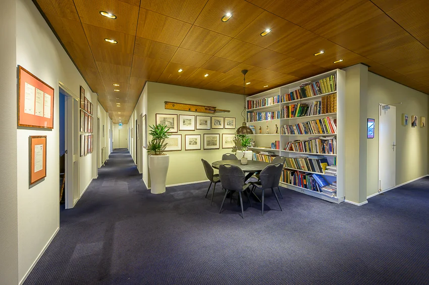 Moderne kantoorruimte met een vergadertafel, boekenwand en kunst aan de muren in de Linschotenstraat.