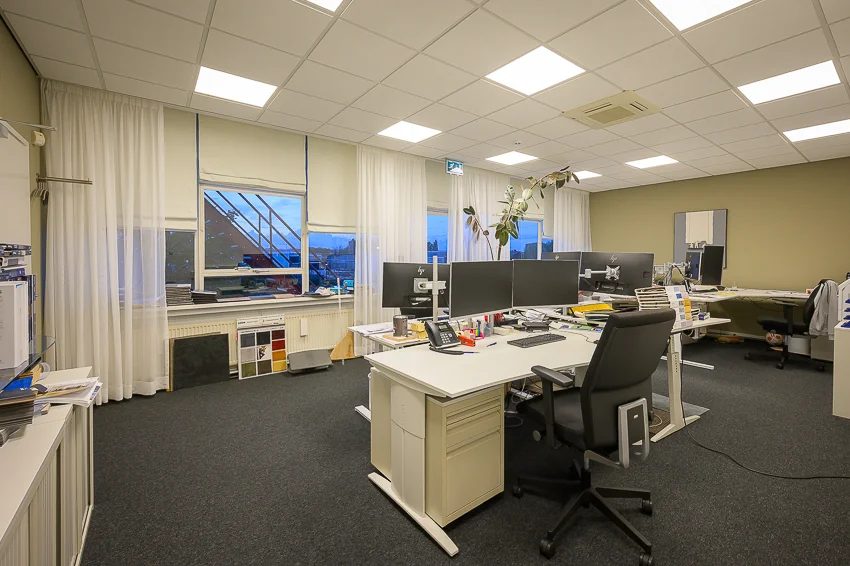 Modern kantoorinterieur aan de Linschotenstraat met meerdere bureaus, computerschermen en grote ramen met uitzicht.