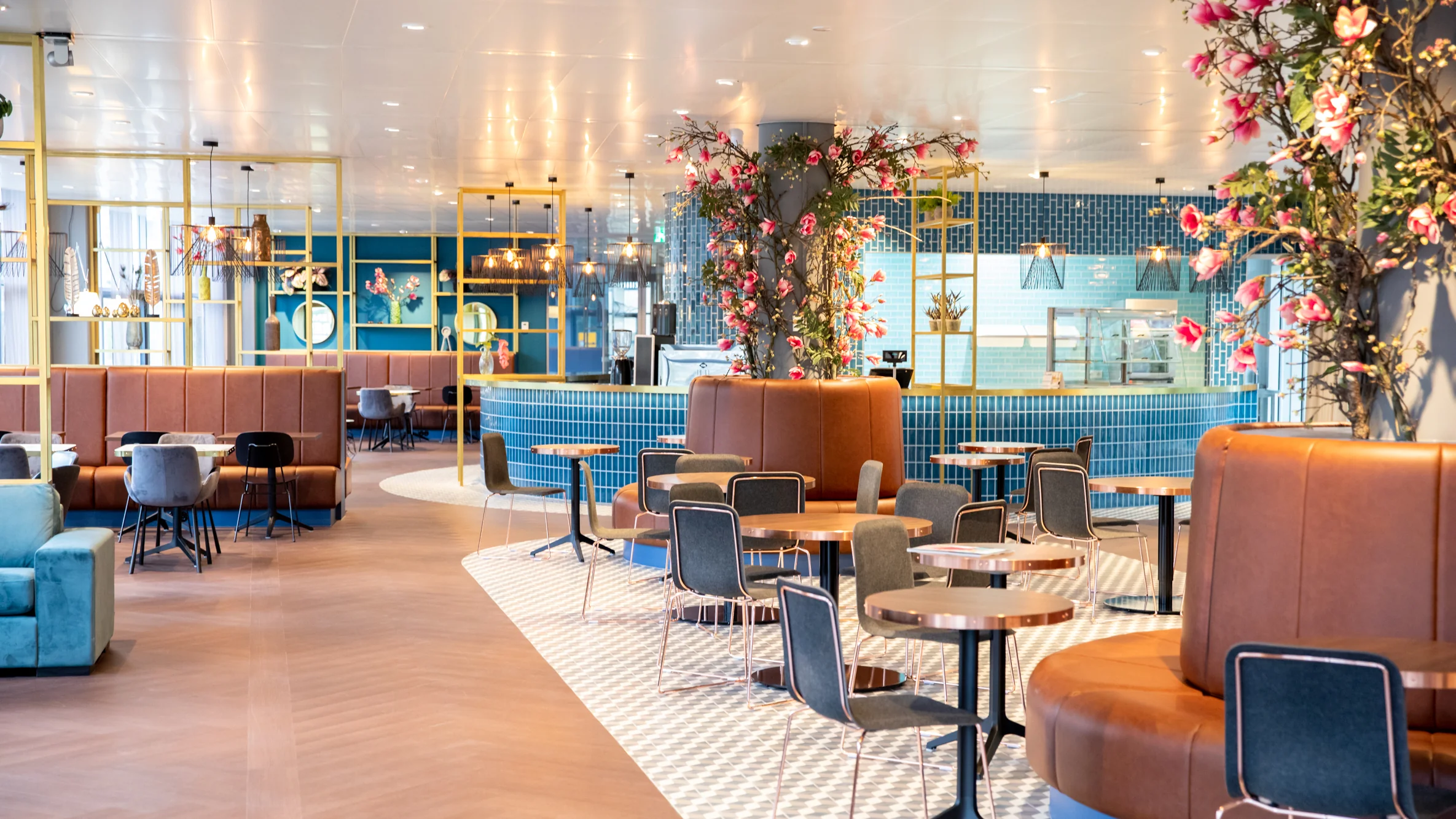 Modern restaurantinterieur aan de Burgemeester van Karnebeeklaan met kleurrijke meubels, bloemendecoratie en open indeling.