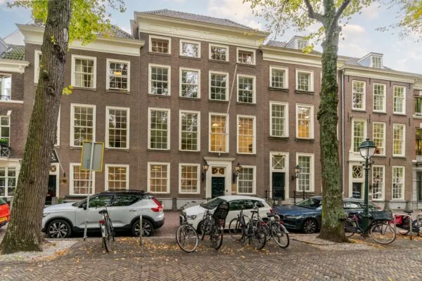 Gevels van historische herenhuizen aan het Lange Voorhout in Den Haag met geparkeerde auto's en fietsen op de voorgrond.