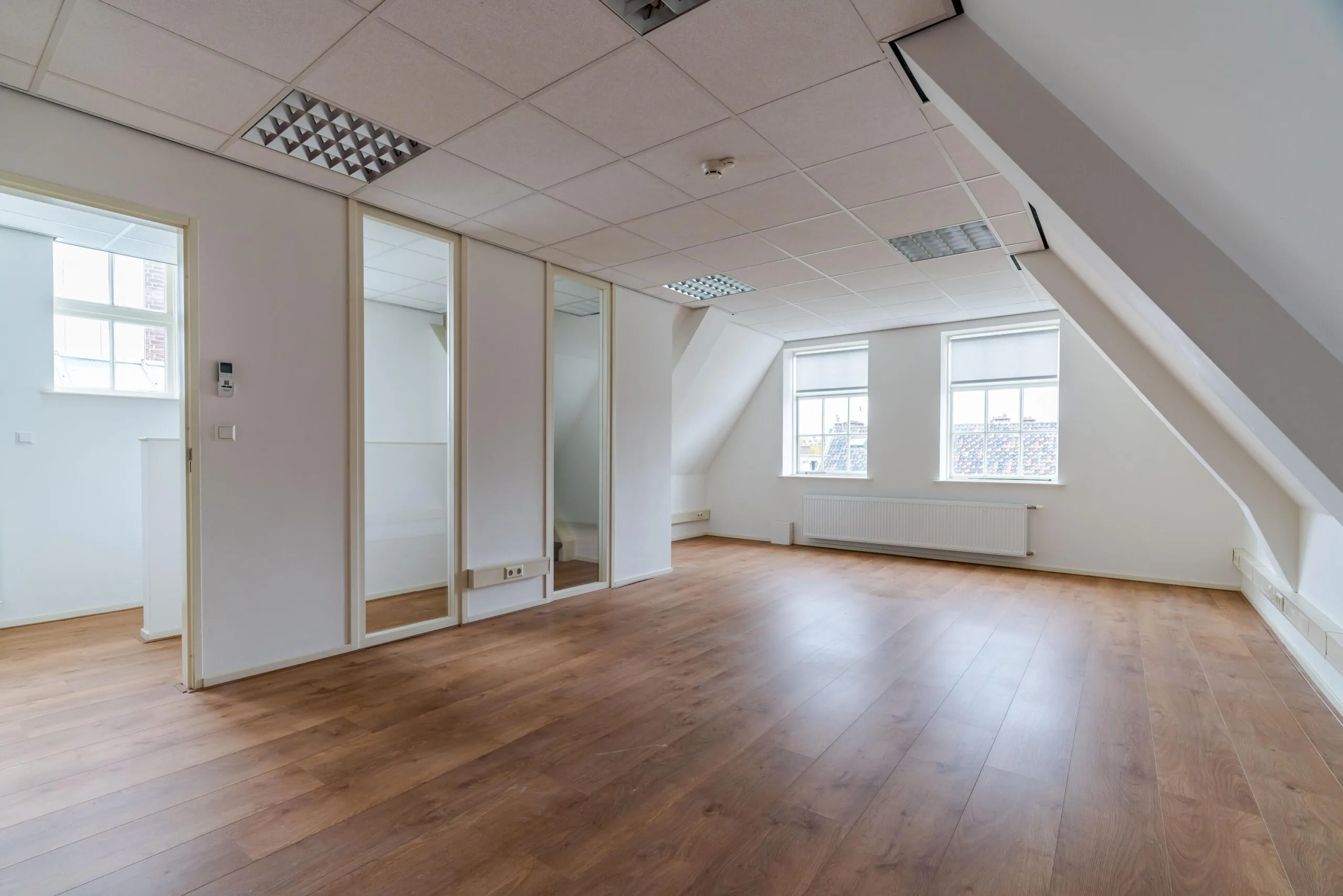 Licht en modern zolderappartement aan het Lange Voorhout met houten vloer, schuine wanden en grote ramen.
