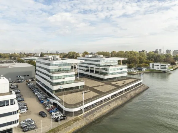 Modern kantoorgebouw aan de Havenstraat in Rotterdam met uitzicht op het water en omringd door geparkeerde auto's.