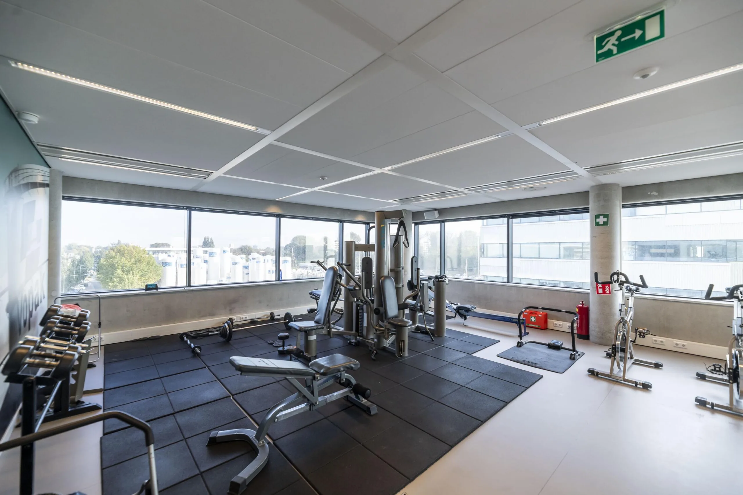 Moderne fitnessruimte in een bedrijfsgebouw aan de Havenstraat met krachttoestellen, halters en cardio-apparatuur.