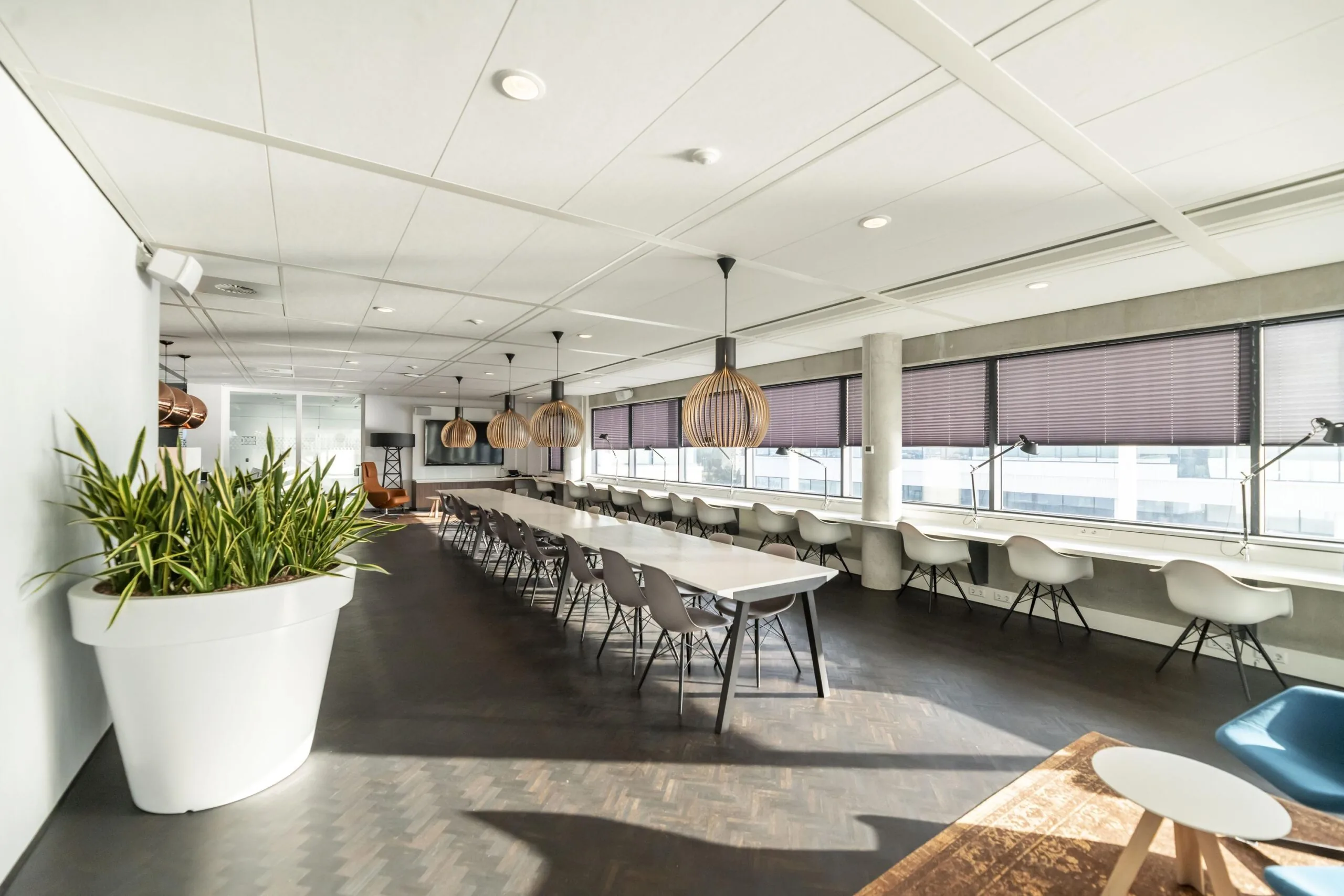 Moderne, lichte kantoorruimte aan de Havenstraat met lange werktafels, ergonomische stoelen en grote ramen met jaloezieën.